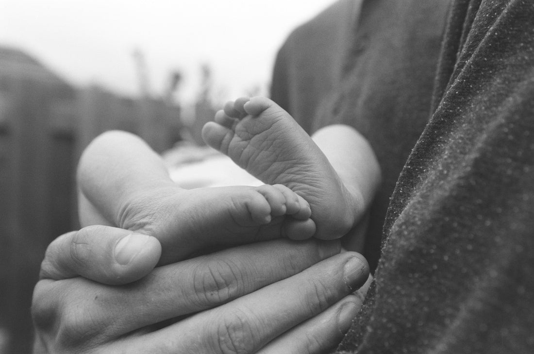 Un parent tenant le pied d'un bébé pour montrer comment mesurer les pieds de bébé correctement
